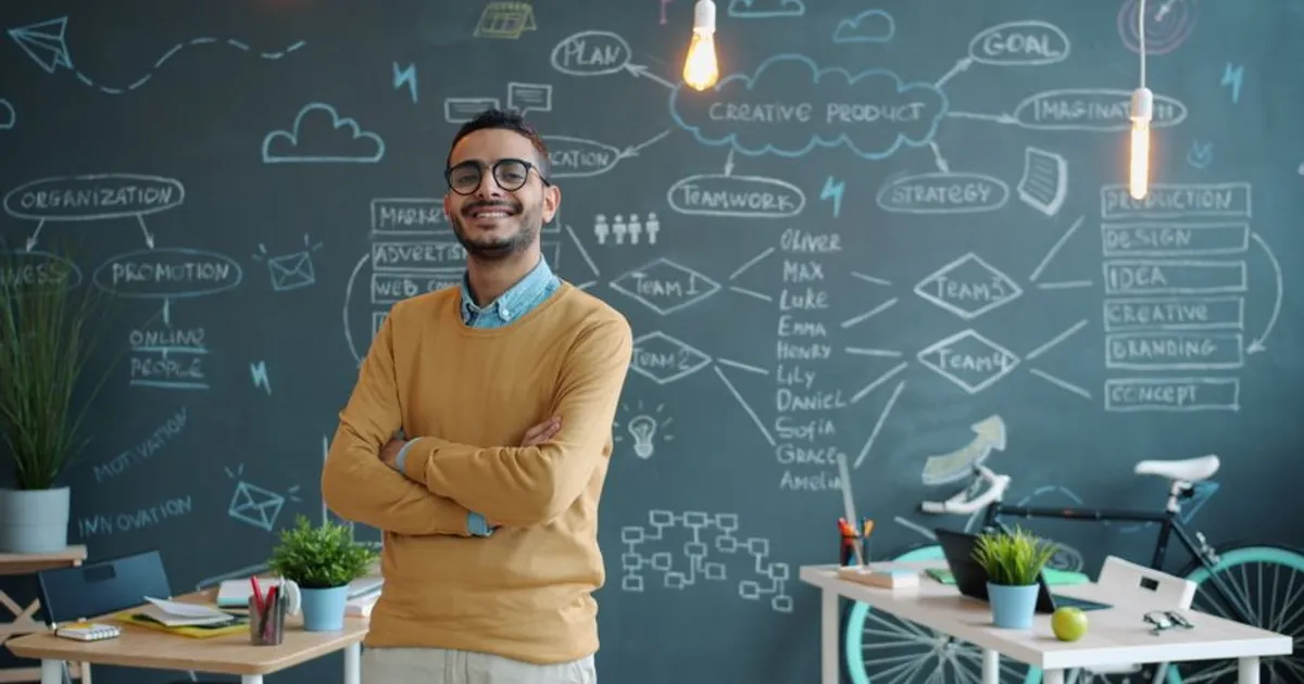 Young entrepreneur smiling in a modern office with creative chalkboard.