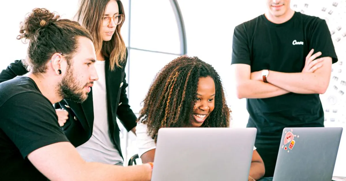 A diverse group of young professionals collaborating enthusiastically in a bright, modern workspace.