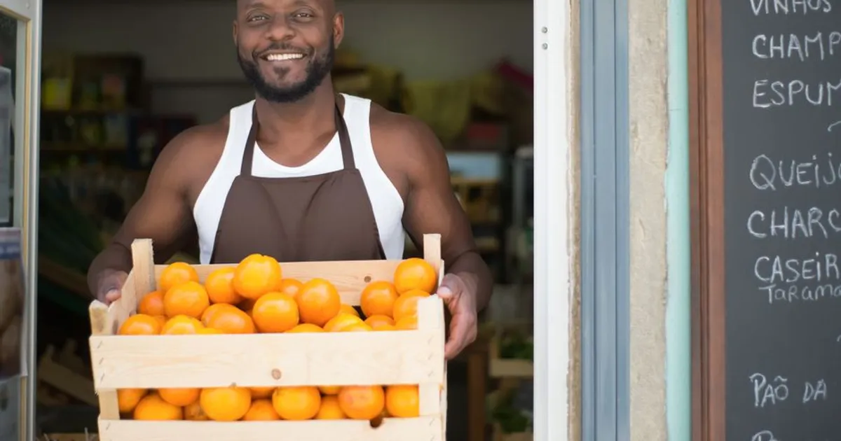 Happy vendor holding a crate of oranges at a local store in Portugal.