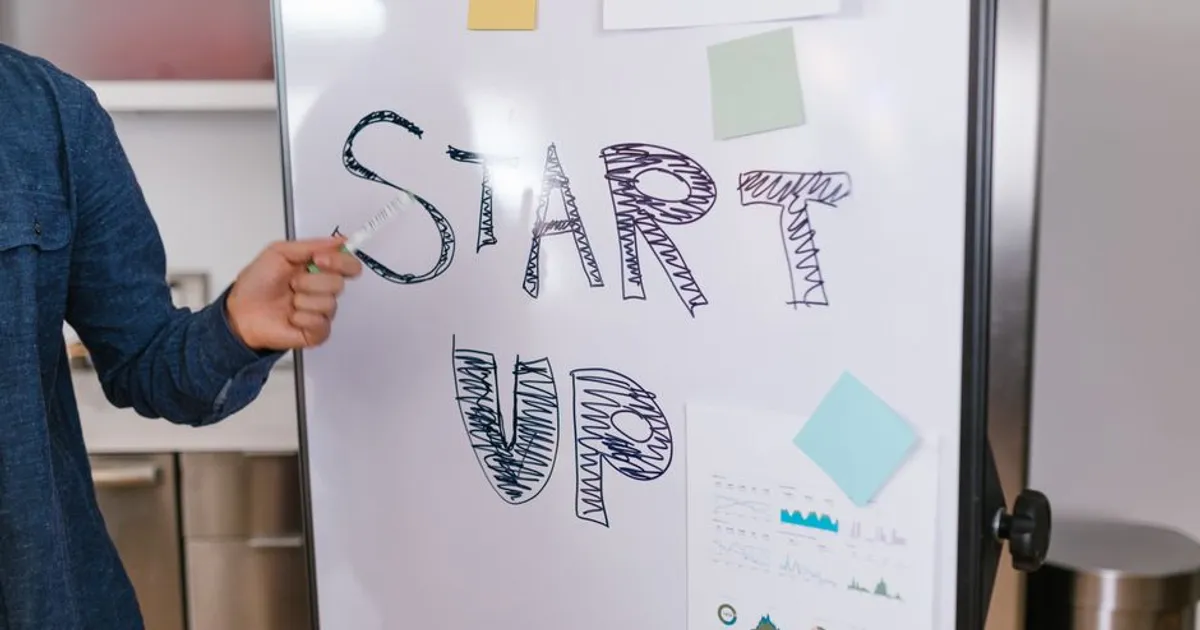 A person presents a startup idea on a whiteboard in an office setting, emphasizing entrepreneurship.