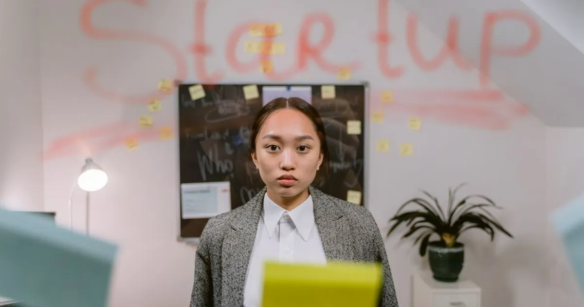 A young professional woman standing in a startup office with creative elements.