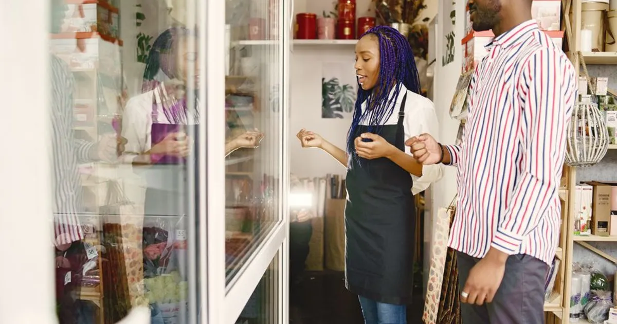 A florist and customer engage in a discussion about products in a cozy flower shop.
