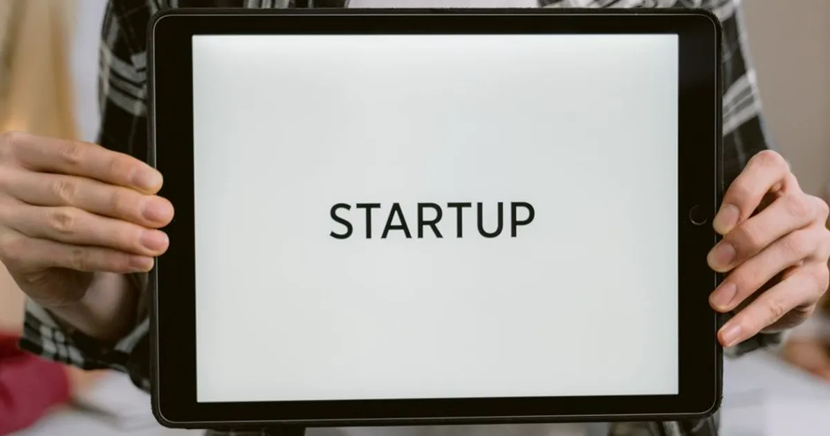 Person holding a digital tablet displaying the word 'STARTUP', representing new business concepts.