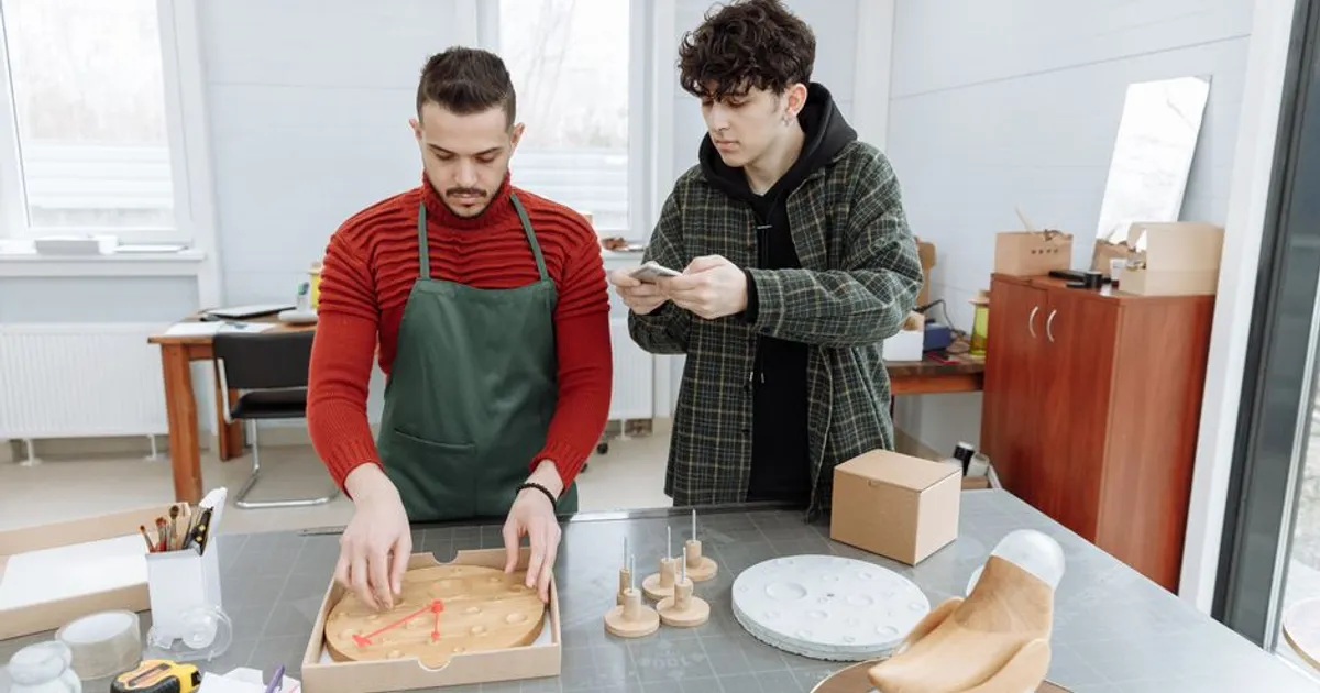 Two men in a creative workspace assembling clocks, capturing industrial and craft elements.