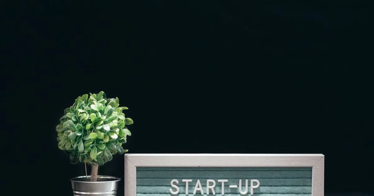 A modern close-up of a start-up theme with a potted plant and text board on a black background.