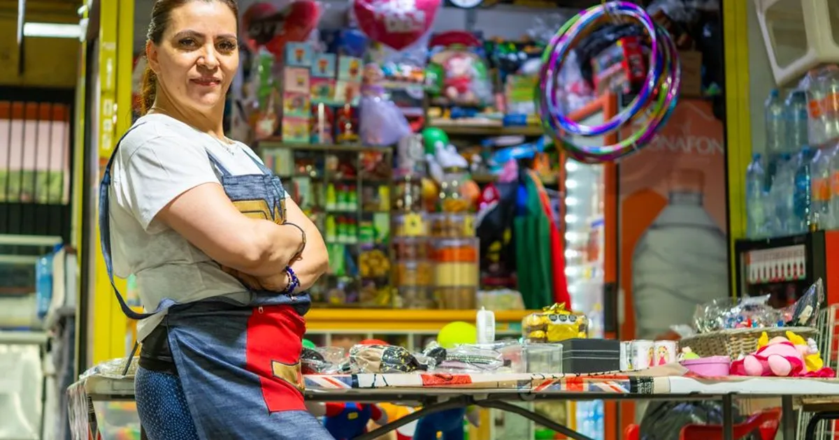 Latin American woman proudly standing at her vibrant Ciudad de México market stall.