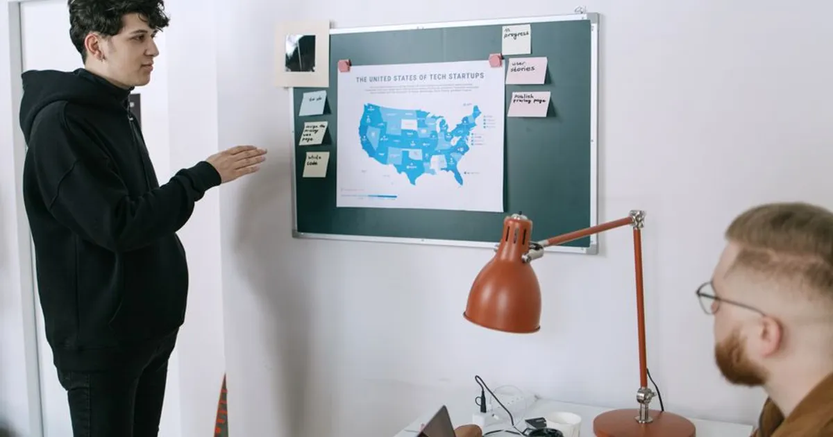 Business meeting discussing startup plans with a map of the United States in a modern office setting.